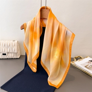 Detail of orange gradient silk scarf with satin luster on a wooden hanger