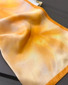 Detailed view of floral silk scarf with orange gradient and smooth satin texture