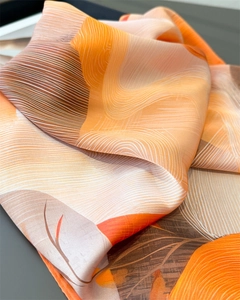 Close-up of a gradient satin scarf showing its smooth texture and elegant orange patterns
