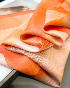 Detail of silk scarf showing orange wave patterns and premium glossy texture fabric