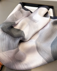 Detailed view of luxury silk scarf with gradient abstract waves and premium gift box