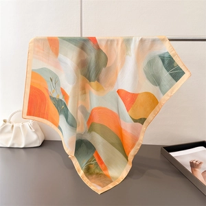 Detail of silk square scarf with abstract orange and green print on a minimal metal hanger