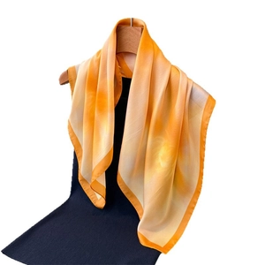 Elegant silk-like scarf with orange marble pattern hanging on a wooden hanger