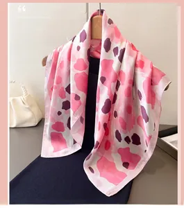 Détail d'un foulard en soie imprimé léopard rose drapé sur un cintre en bois naturel