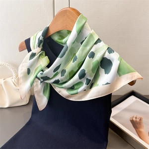 Détail d'un foulard en soie léopard avec motifs verts et bordures blanches élégantes