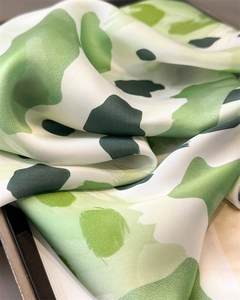 Gros plan sur la texture satinée et les motifs abstraits verts de ce foulard élégant