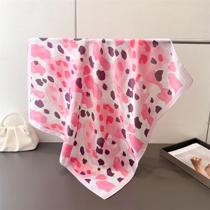 Détail d'un foulard en soie rose à motif léopard drapé sur un support en métal