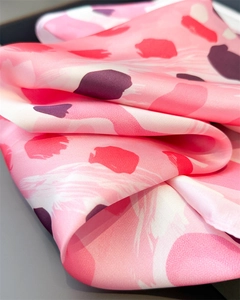 Détail d'un foulard en satin à imprimé léopard rose montrant la texture douce du tissu