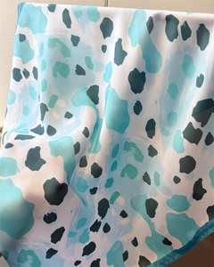 Détail d'un foulard en soie léopard montrant la texture lisse et la couture fine des bords
