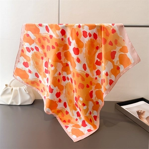 Détail d'un foulard en soie à imprimé léopard orange montrant la texture fluide et douce