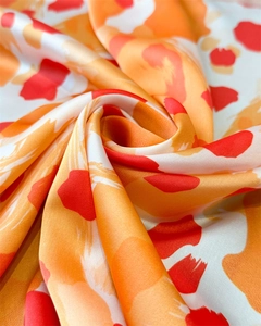 Vue macro d'un foulard en soie aux motifs léopard tourbillonnants orange et rouge