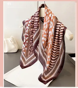 Détail d'un foulard en soie à imprimé léopard marron et orange sur un cintre blanc