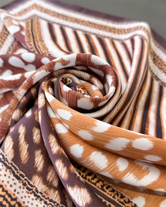 Gros plan d'un foulard carré en soie avec imprimés léopard et animaliers au fini brillant