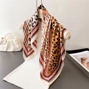 Détail d'un foulard carré en soie à motif léopard drapé avec un sac à main en perles