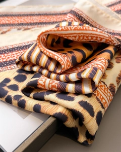 Gros plan d'un foulard en satin léopard avec des rayures géométriques orange et noires