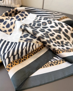 Detailed view of leopard and zebra print silk scarf with satin texture and green border