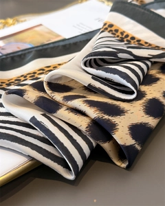 Macro detail of silk-like scarf with leopard and zebra prints and green rolled edges