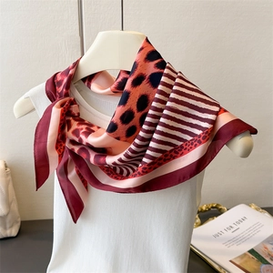 Detail of silk-like leopard print square scarf with elegant red and black stripe pattern