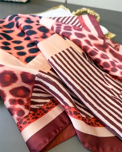 Detail of silk scarf with leopard print and geometric stripes in rich burgundy and gold
