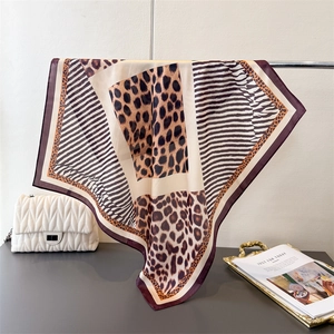 Detail of leopard and zebra print silk-like square scarf draped on a gold stand