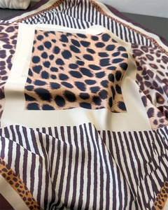 Close-up of leopard print satin silk scarf with orange animal motifs and smooth texture