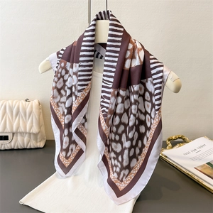 Leopard and geometric print silk scarf displayed on a beige hanger with elegant dress