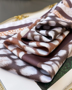 Detailed close-up of leopard print silk scarf with smooth satin texture on elegant background