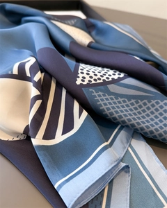 Close-up detail of geometric patterns and silk-like fabric texture on a blue neck scarf