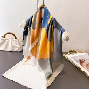 Elegant abstract color block square silk scarf displayed on a mannequin and white blouse