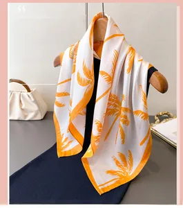 Detail of white silk-like scarf with orange palm leaf print and finished hem edge