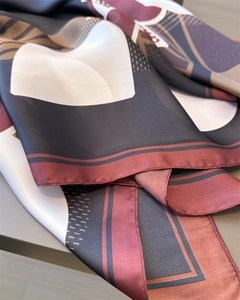 Macro detail of geometric print silk scarf with luxury burgundy and gold pattern finish