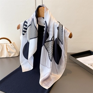 Elegant black and white geometric silk scarf draped on hanger with minimalist decor