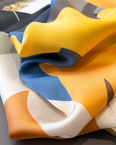 Close-up of geometric color block satin scarf showing silk texture and neat edge stitching