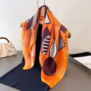 Elegant geometric silk scarf with orange and purple patterns on a wooden hanger