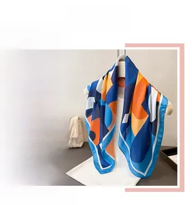 Vue détaillée d'un foulard en soie aux motifs géométriques bleu et orange contrastés