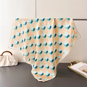 Détail du foulard carré en soie avec motif géométrique à carreaux et drapé élégant