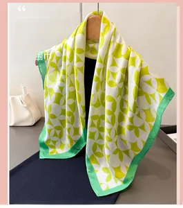 Detail of silk scarf featuring green and yellow geometric patterns on a wooden hanger