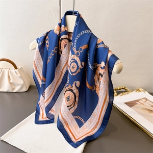 Elegant silk-like square scarf featuring golden chain prints on a white mannequin stand