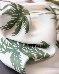 Macro detail of silky palm leaf print scarf showing smooth fabric texture and drape