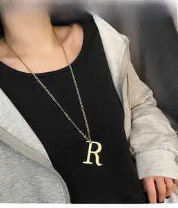 Detailed view of long gold necklace featuring a minimalist letter R tag pendant