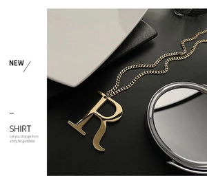 Macro detail of gold letter R pendant necklace on a minimalist black and white background