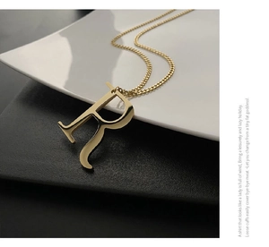 Macro detail of gold-plated capital letter R pendant necklace with polished mirror finish