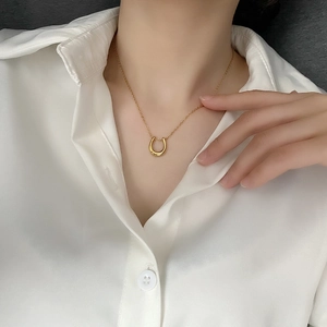 Polished gold U-shaped horseshoe pendant necklace on a minimalist fine chain for women