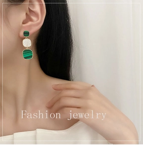 Close-up of geometric malachite dangle earrings with paved rhinestones on female model