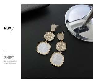 Detail of three-tier geometric earrings with gold trim and mother of pearl inlay