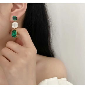 Close-up of elegant gold earrings with green malachite texture and micro-pave zircons