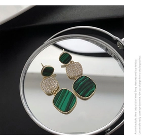 Detailed view of gold triple-tiered geometric earrings with green malachite and crystals