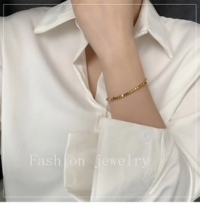 Detailed view of a gold cube bead titanium bracelet with adjustable link chain on wrist