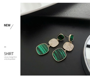 Detailed view of layered geometric drop earrings with malachite texture and pavé crystals