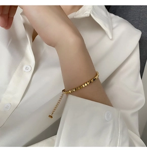 Close-up of a minimalist gold square bead bracelet with adjustable chain on a wrist